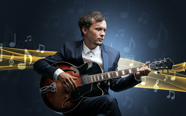Obraz premium Young male musician playing on his guitar with musical notes around