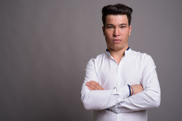 Portrait of young Asian businessman against gray background
