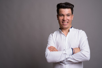Portrait of young Asian businessman against gray background