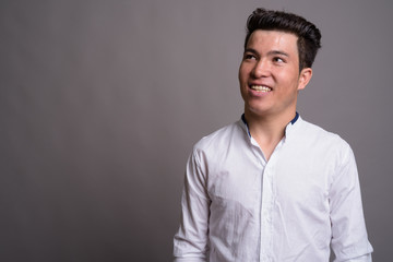Portrait of young Asian businessman against gray background