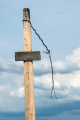Blank wooden signpost and barbed wire against the sky