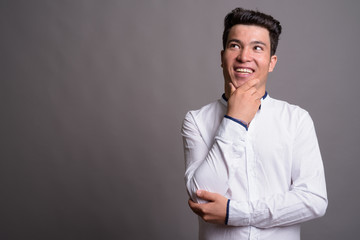 Portrait of young Asian businessman against gray background