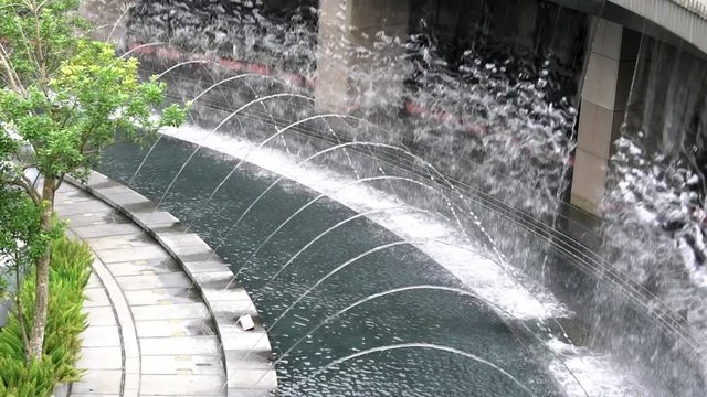 Slow Motion of big artificial waterfall in the middle of the Daan park at Taipei city. Water falling down rock wall. Beautiful fountain-Dan
