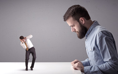 Young professional businessman being angry with an other miniature businessman in front of a...