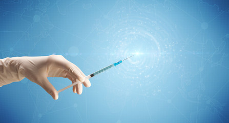 Naklejka premium Female doctor hand holding syringe with blue background and shine