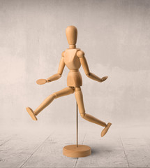 Wooden mannequin posed in front of a greyish background