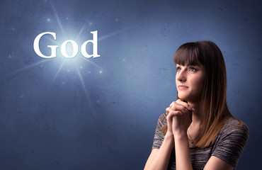 Young woman praying on a blue background with the word God written above her