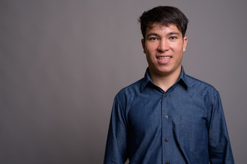 Young Asian man wearing blue shirt against gray background