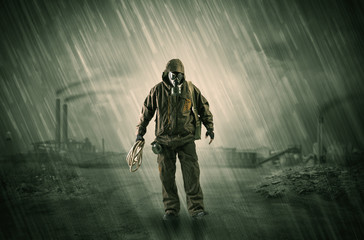 Gas masked survival man coming with arms on his hand  in a demolished dark environment 
