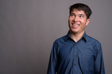 Young Asian man wearing blue shirt against gray background