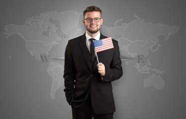 Cheerful businessman standing in front of a map with flag on his hand
