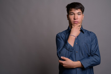 Young Asian man wearing blue shirt against gray background