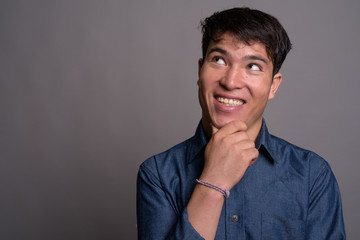 Young Asian man wearing blue shirt against gray background