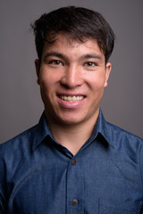 Fototapeta premium Young Asian man wearing blue shirt against gray background