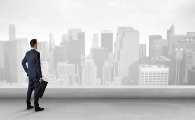 Businessman standing with his back on a roof with objects in his hand
