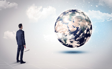 Businessman standing with his back with objects in his hand and looking at the globe, courtesy of NASA
