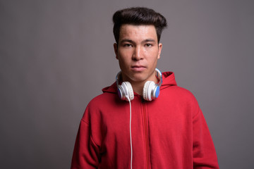 Young Asian man wearing headphones against gray background