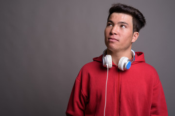 Young Asian man wearing headphones against gray background