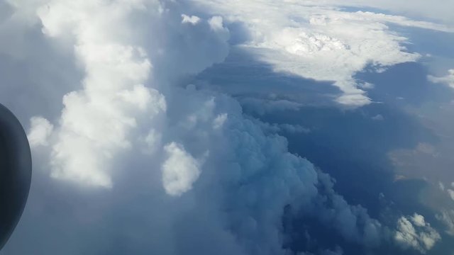  Stunning view of huge and fluffy white clouds from an airplane window on sunny day in summer. Sky clouds look like raggy mountains.
