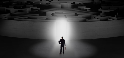 Businessman getting ready to enter a concentric labyrinth with lighted entrance concept
