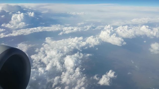  Mysterious view of hilly and snowy white clouds from an airplane window on sunny day in summer.The beaming celeste sky looks great