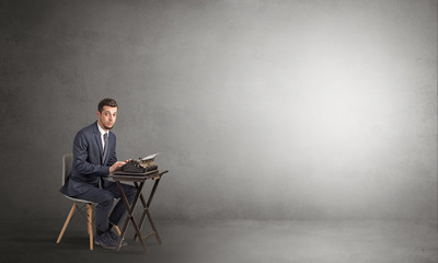 Man working hard on a typewriter in an empty space

