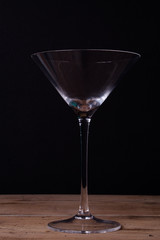 Elegant martini glass on wooden table with black wall background