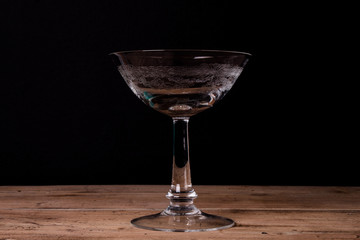 Elegant liqueur glass on wooden table with black wall background