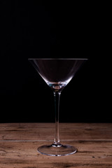 Elegant martini glass on wooden table with black wall background
