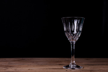 Elegant liqueur glass on wooden table with black wall background