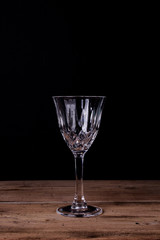 Elegant liqueur glass on wooden table with black wall background