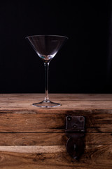 Elegant martini glass on wooden table with black wall background