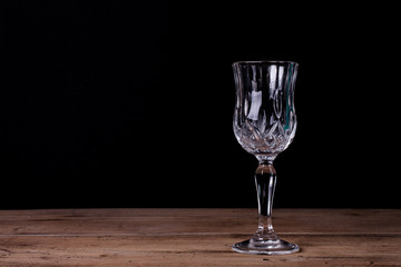Elegant liqueur glass on wooden table with black wall background