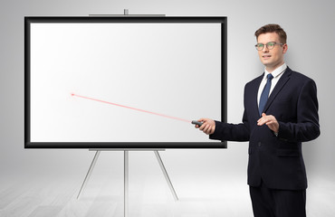 Fototapeta premium Young businessman with laser pointer and copyspace white wall 