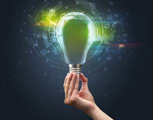 Hand holding light bulb on dark background. New business idea concept