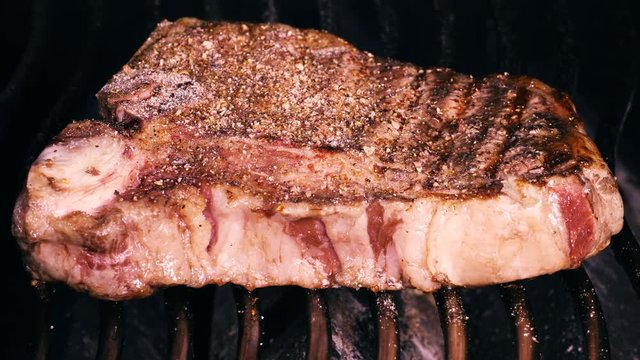 UHD closeup shot of the seasoned t-bone steak on a barbecue grill