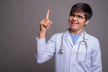 Young Asian man doctor against gray background