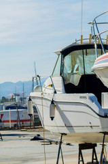 Fototapeta premium Boat on stand on the shore, close up on the part of the yacht, luxury ship, maintenance and parking place boat