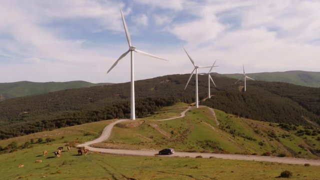 Car passing by windmills in the picturesque mountains of La Rioja, Spain