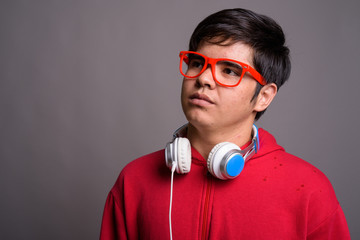 Young Asian teenage boy wearing headphones against gray backgrou