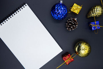 White paper notepad on black table with Christmas tree decor. Winter holiday mockup for logo, lettering or sketch.
