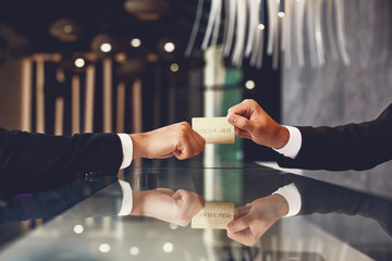 Laconic image of young man in dark suit giving his gold card to the professional receptionist