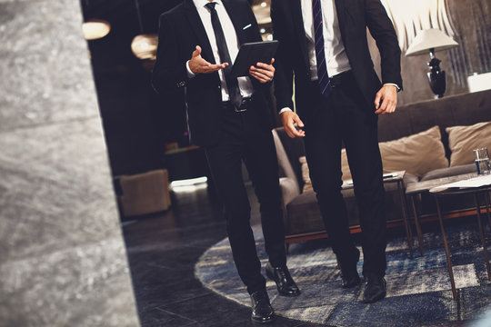 Two elegant business partners having meeting in the hall and using modern tablet