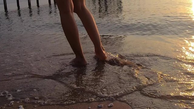 video footage ,Woman legs on the beach sand waves sea at sunrise .