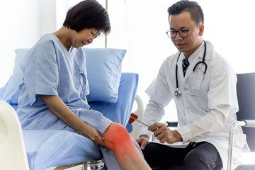 Healthy concept; Doctor examining his old patients knee in hospital