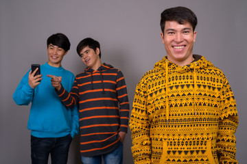 Three young Asian friends together against gray background