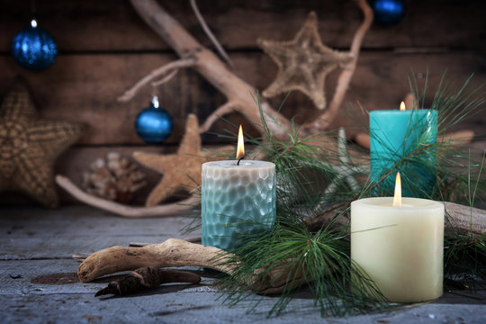 Beach scene of Christmas candles and seaside decor with ornaments on a wooden background