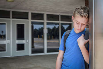 Depressed upset student standing outside school doors