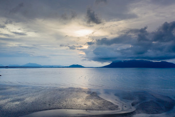 Aerial drone view of sunset and clouds over the ocean at low tide in Sarawak, Malaysian Borneo