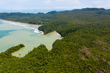 Fototapeta na wymiar Aerial drone view of dense tropical rainforest leading to a remote, rough ocean coastline